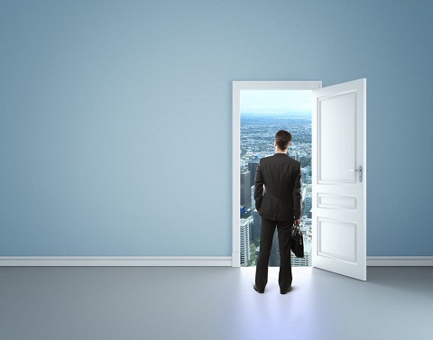 In empty blue room of a house a businessman with briefcase stands in front of an open door with a long-range view of a city