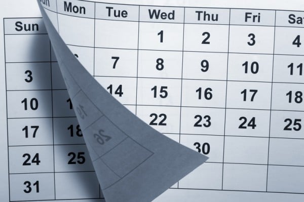 One generic monthly calendar page is being lifted to reveal the beginning of another month