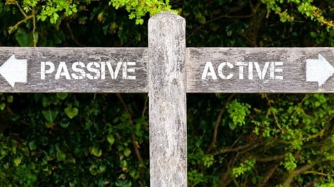 A wooden crossroads sign with the word PASSIVE with an arrow pointing left and the word ACTIVE with an arrow pointing right