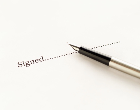 Fountain pen lying on white paper that reads signed