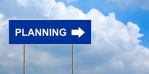 A blue rectangular road sign with the word PLANNING and an arrow pointing to the right in front of sky with white clouds
