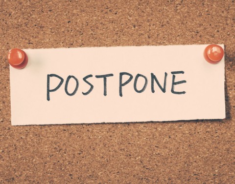 A card reading "postpone" pinned to a bulletin board