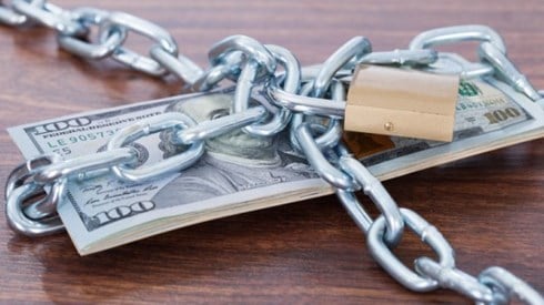 Stack of hundred dollar bills wrapped in chains and padlocked