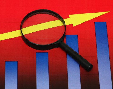 A magnifying glass focuses on part of an arrow that is following the growth of 4 graph bars ascending in value