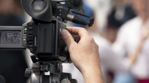 Photographer with a professional camera is filming blurred-out persons