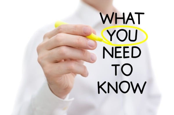 On a glass writing board a businessman has written the words WHAT YOU NEED TO KNOW and has circled in yellow the word YOU