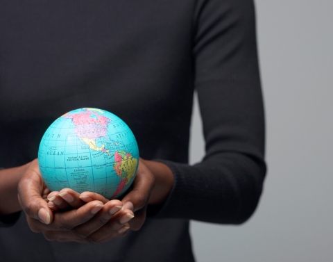 A woman of color holding a small globe in the palms of her hands