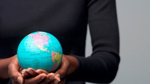A woman of color holding a small globe in the palms of her hands