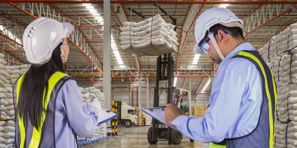 Warehouse Supervisors wearing Hardhats and Reflective Vests Monitor Forklift Safety Using Checklists