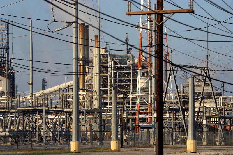 A power transfer station for an electrical plant and industrial type buildings behind with blue sky in background