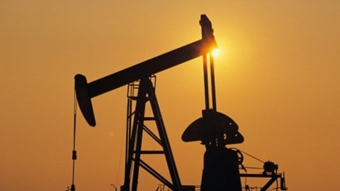 A silhouette of an oil drill against a sunset sky