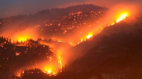 Wildfire viewed at night from distance burning in hills and valleys