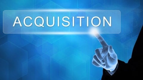 A businessman touches and activates a giant button marked as ACQUISITION