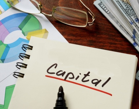 Capital Notebook with graphs, eyeglasses, and a stack of money