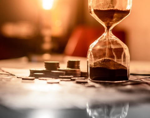 Coins sitting next to an hourglass