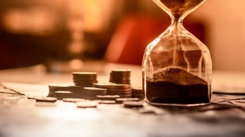 Coins sitting next to an hourglass