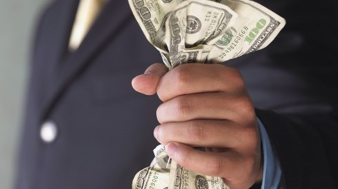 A businessman in a blue suit holding three crinked one hundred dollar bills and one fifty dollar bill