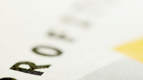 The word PROFIT in black type on white paper with the end of the word blurred and a yellow sticky note on the bottom