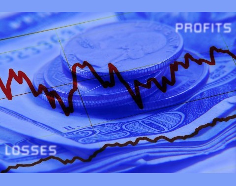 Graph showing increases and decreases in front of a background of dollars bills and change