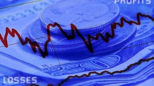 Graph showing increases and decreases in front of a background of dollars bills and change