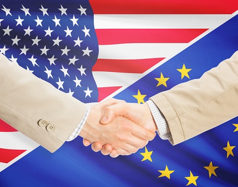 Businessmen shaking hands in front of US and EU flags