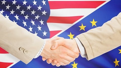 Businessmen shaking hands in front of US and EU flags