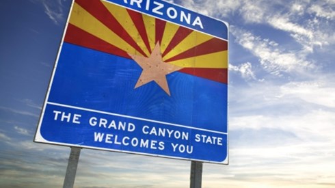 A welcome sign at the border of Arizona saying ARIZONA and THE GRAND CANYON STATE WELCOMES YOU