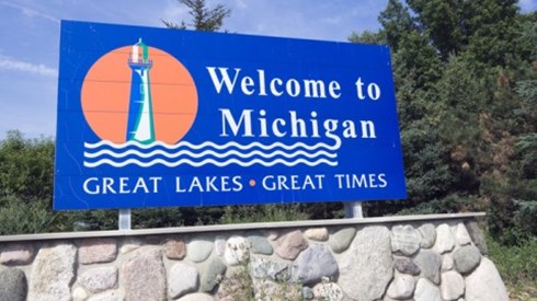 Welcome to Michigan sign with lighthouse, lake icon and the words GREAT LAKES, GREAT TIMES