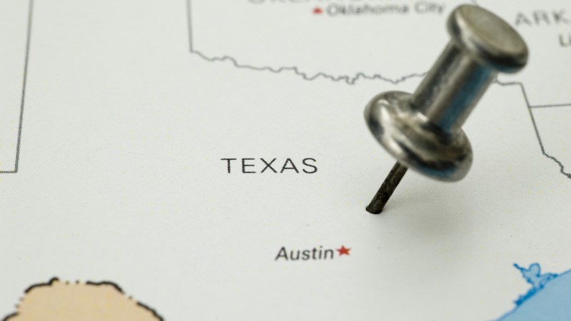 Outline map of the state of Texas with a thumbtack pushed into the state above Austin