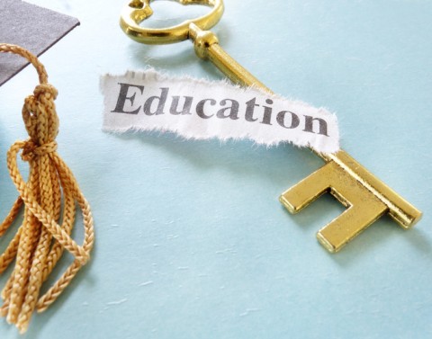 Graduation cap corner and tassel, a golden skeleton key and the word Education torn from a newspaper