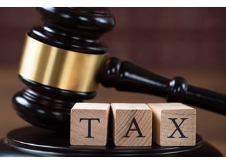 Gavel and base behind three building blocks that spell the word TAX