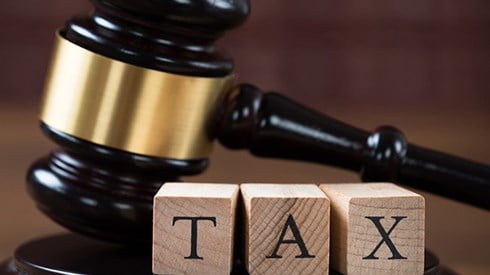 Gavel and base behind three building blocks that spell the word TAX