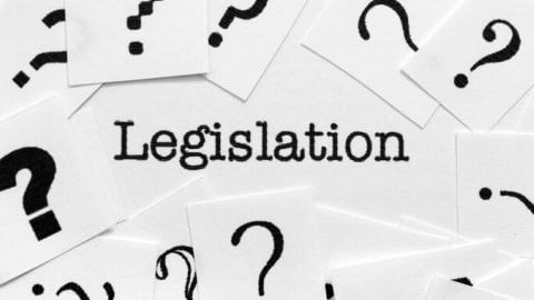 Several pieces of white paper with black question marks surrounding the word legislation