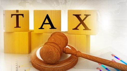 Wooden blocks with TAX printed on them in background with a wooden gavel on top of graphs in the foreground
