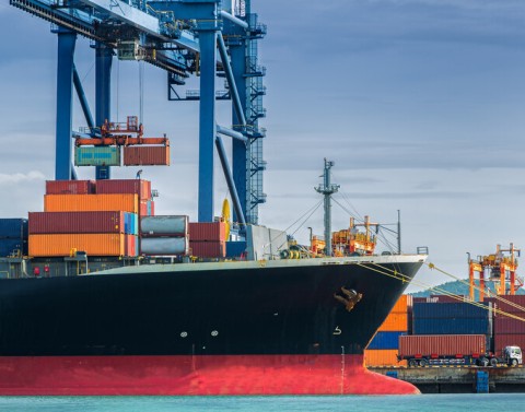 Freight ship is docked in a port and is receiving more freight.