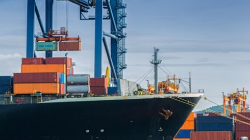 Freight ship is docked in a port and is receiving more freight.