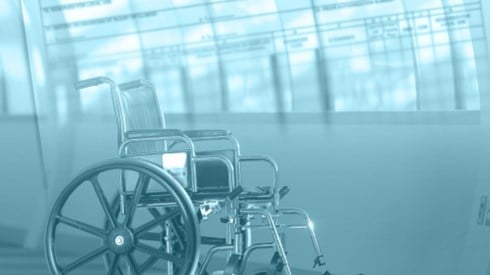 An empty wheelchair in a medical facility with medical forms superimposed in background