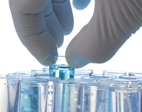 Gloved hand retrieving vials with blue liquid