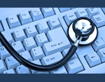 A stethoscope is lying on a computer keyboard