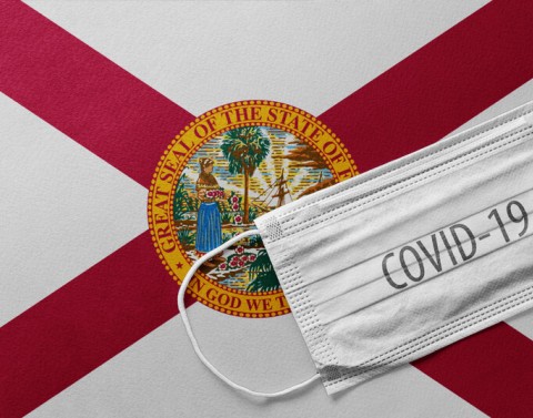 The Florida flag with a medical mask and COVID-19 written on it