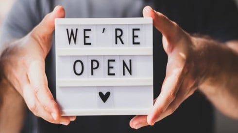 Hands holding We Are Open sign after pandemic