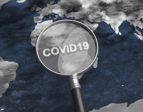 Over a flat globe a magnifying glass with COVID19 printed on the lens is focusing on Africa