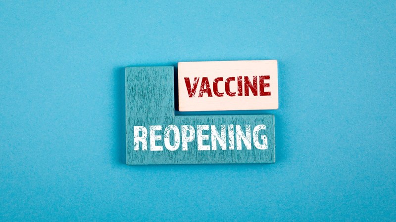 Stacked wooden blocks with the words Reopening and Vaccine written on them