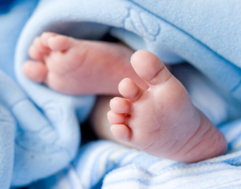 Blue baby blanket with baby soles of feet exposed