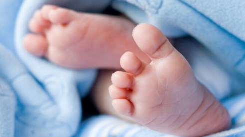 Blue baby blanket with baby soles of feet exposed