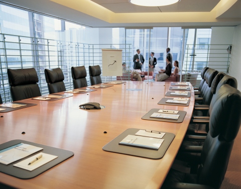 A conference room table with a group of businesspeople having a meeting in the background