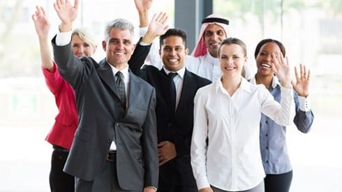 Multi-national group of male and female business professionals waving.