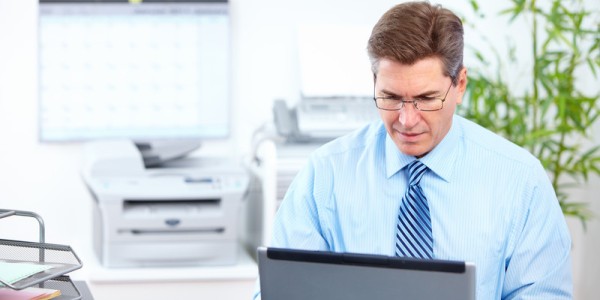 Businessman using laptop computer with office equipment blurred in the background