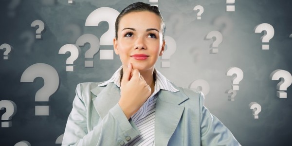 Businesswoman contemplates surrounded by question marks