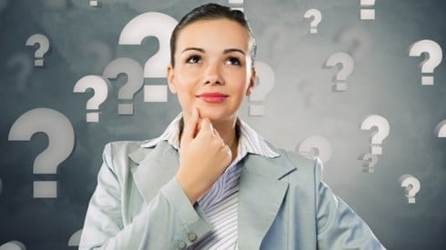 Businesswoman contemplates surrounded by question marks